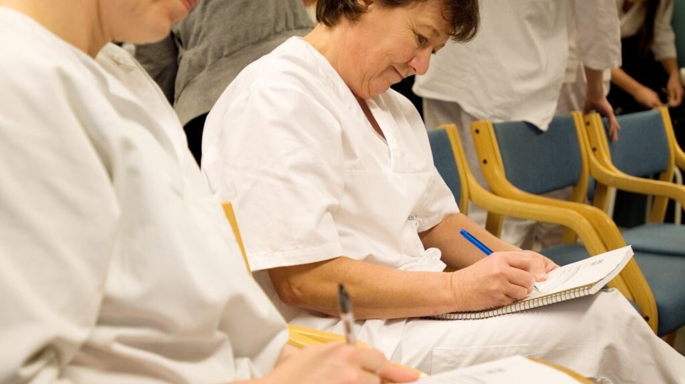 Bildet viser to sykepleiere som sitter og noterer