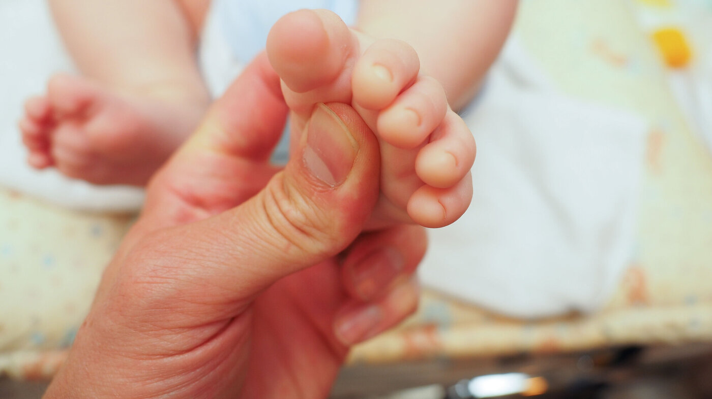 Bildet viser en baby som får massasje under den ene foten.