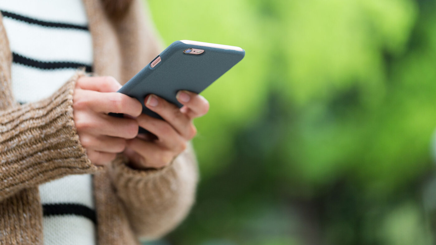 Bildet viser en kvinnehånd som holder en smarttelefon.