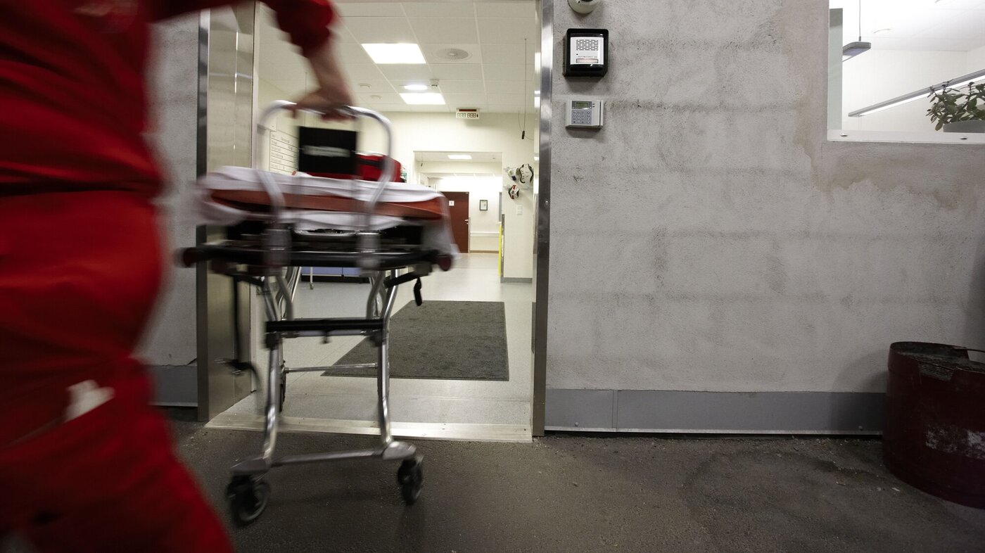 En mann i ambulanseuniform løper inn på sykehuset med en båre