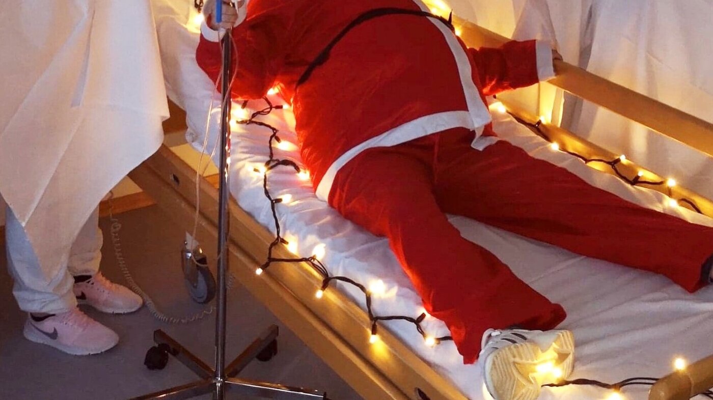 Ida Hareide, Hareid sjukeheim Bildet viser julenissen i en pasientseng omgitt av pleiere i Lucia-drakter.
