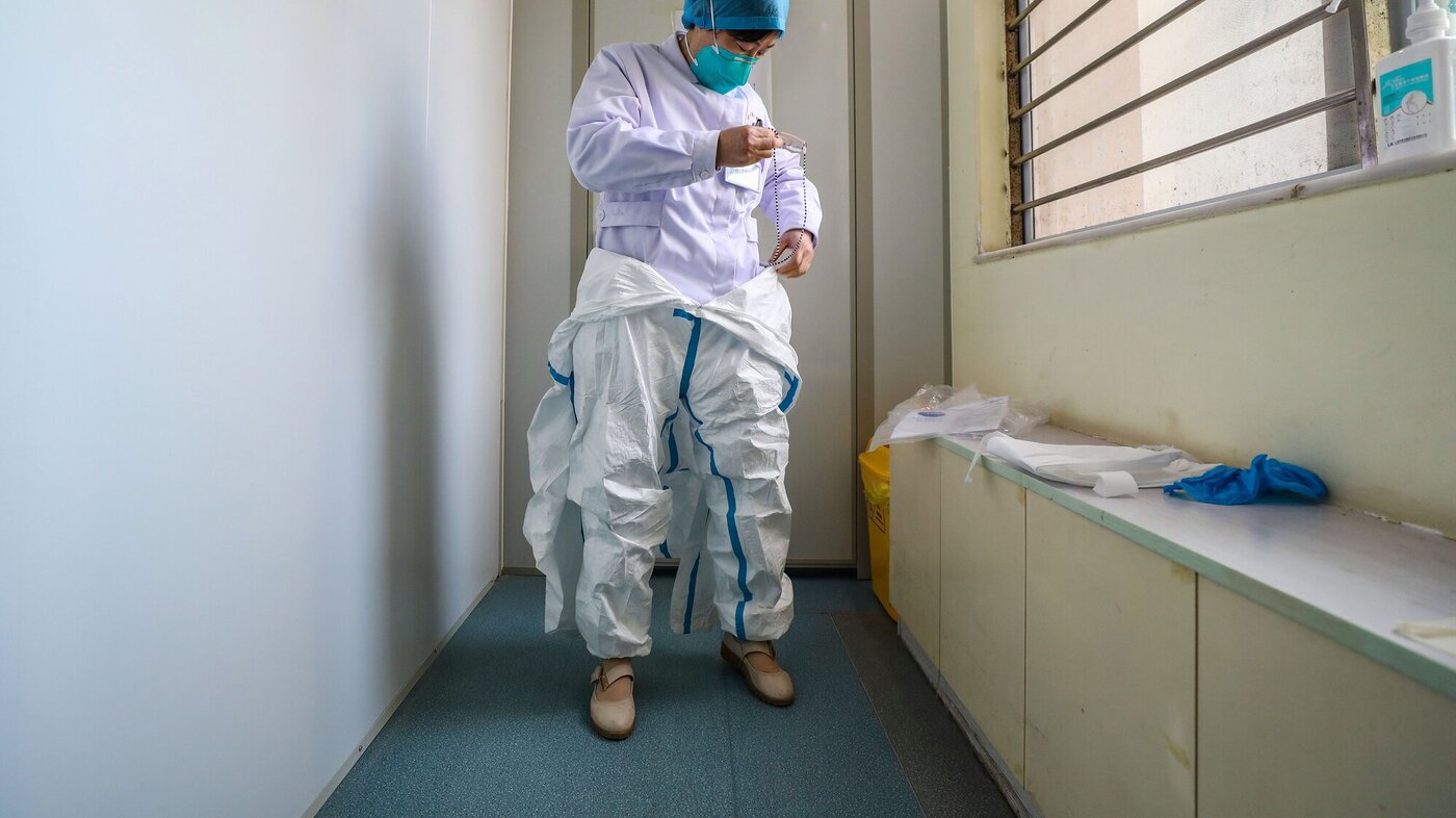 Bildet viser en lege som tar på seg smittevernutstyr.