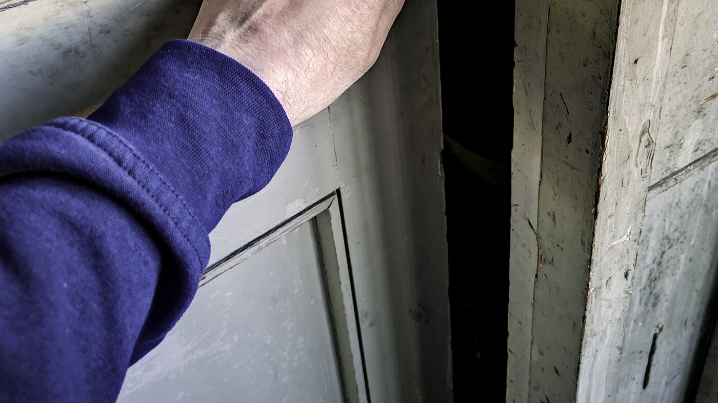 Bildet viser en arm som lukker en gammel dør