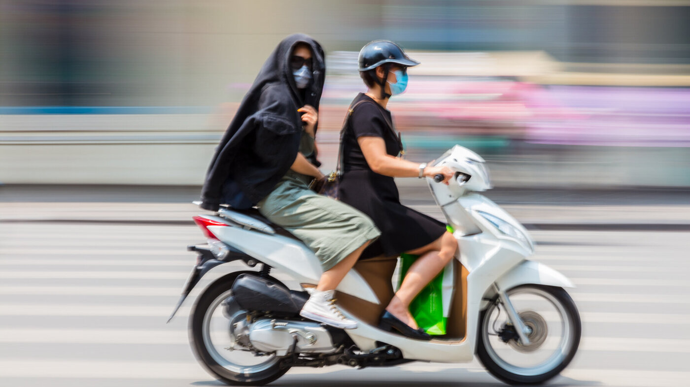 Bildet viser to på scooter som bruker munnbind.