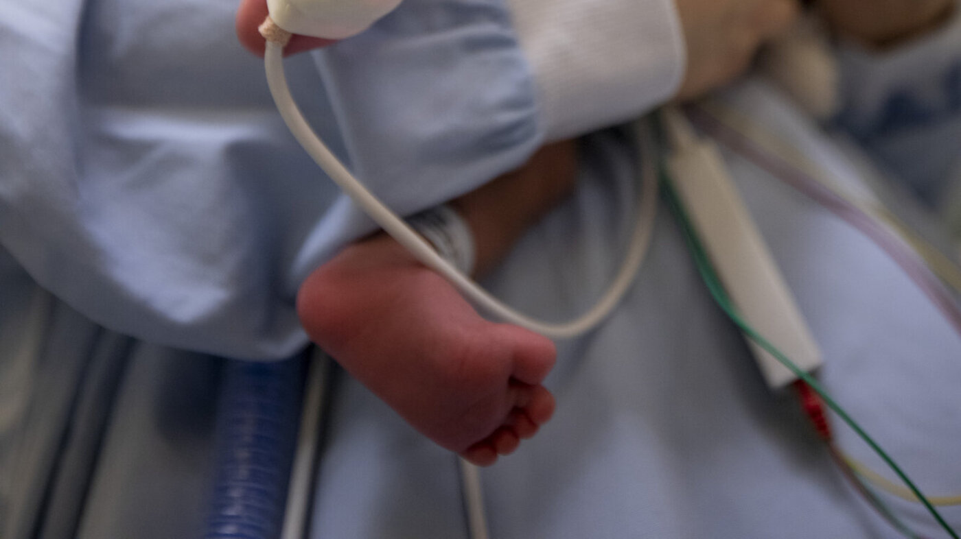 Bildet viser Julie Dahle som holder en liten baby, med oksygenmetningsmåler på foten.