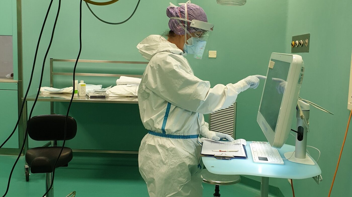 Bildet viser en sykepleiere som står og trykker på en skjerm.