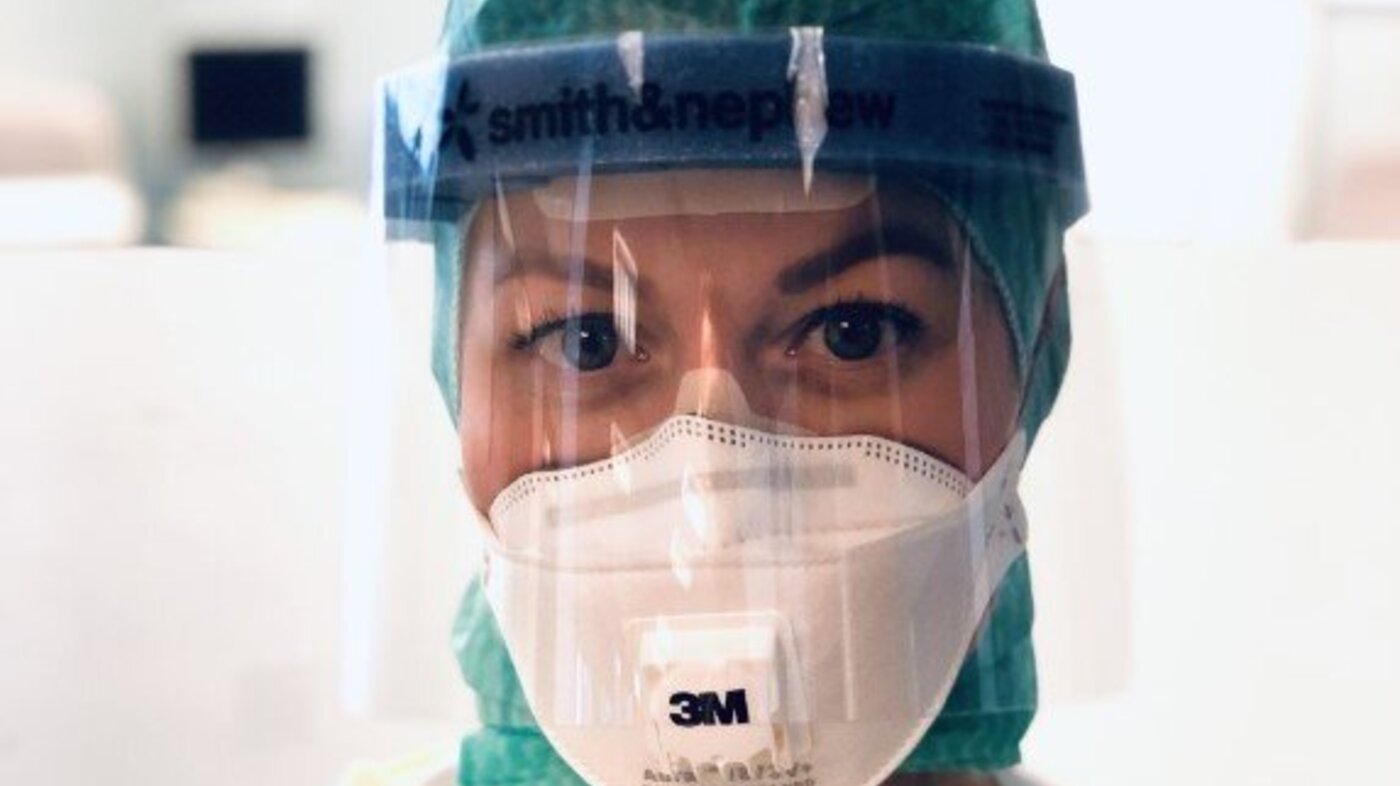 Bildet viser en sykepleier med beskyttelsesmaske og -visir