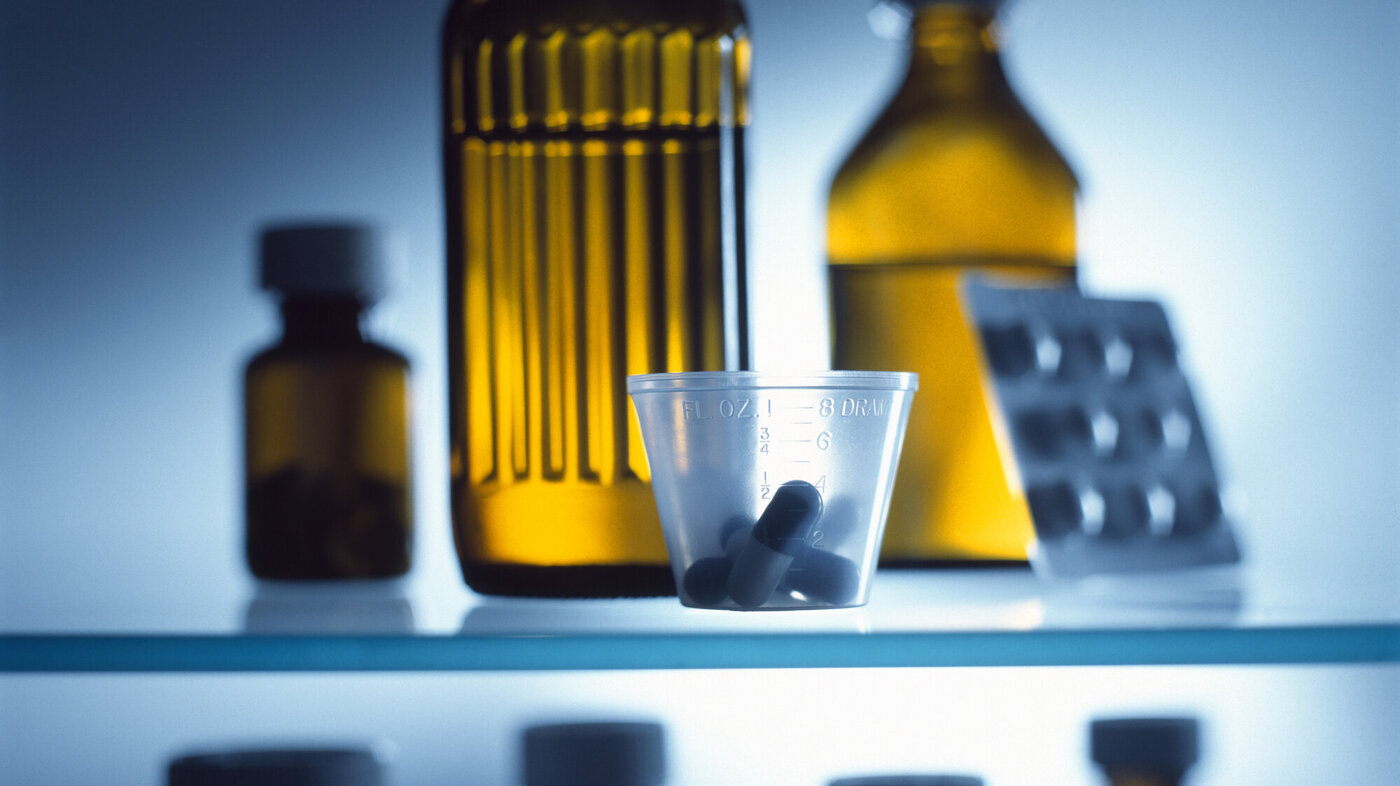Bildet viser ulike flasker med legemidler, et brett med piller og et medisinbeger med piller.