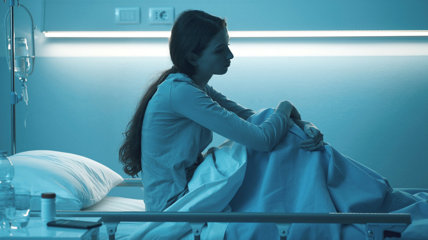 Bildet viser en ung kvinne i en sykehusseng.