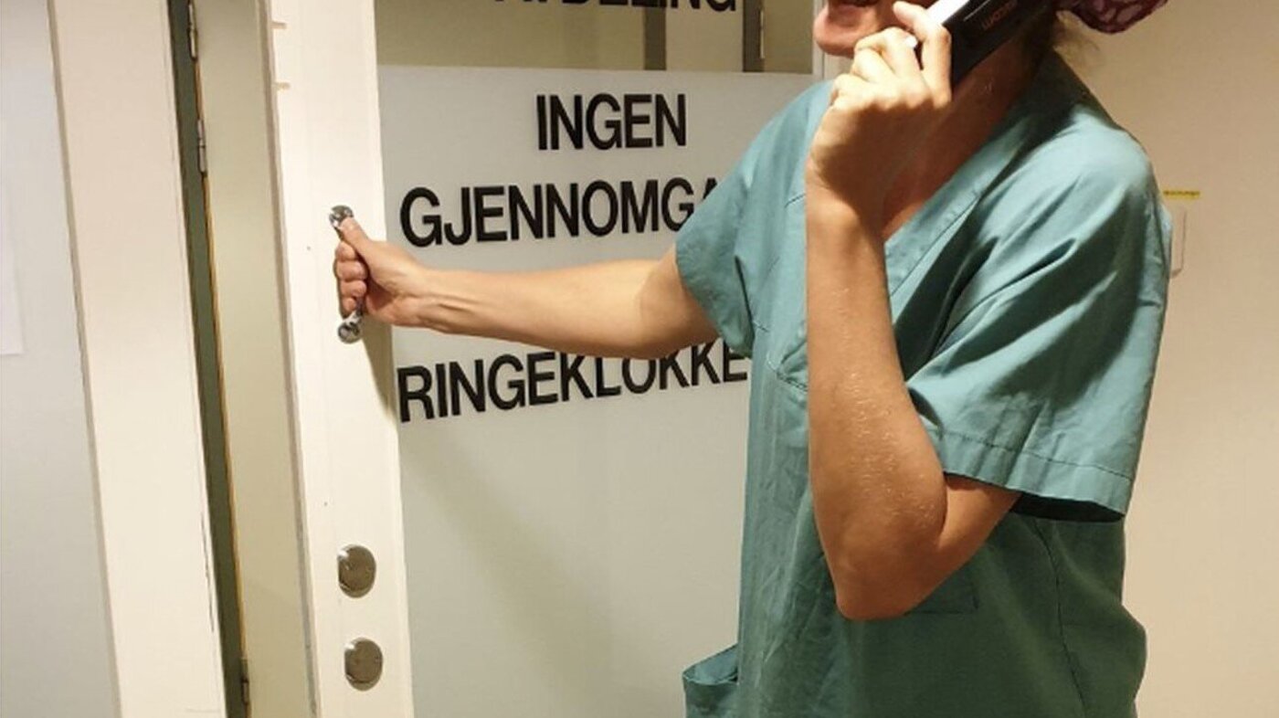 Bildet viser en operasjonssykepleier som åpner døren inn til operasjonsavdelingen.