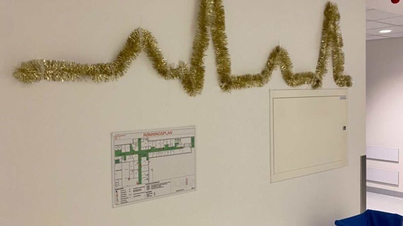 Jul Bildet viser en vegg som er pyntet med glitterlenker formet som en hjerterytme.