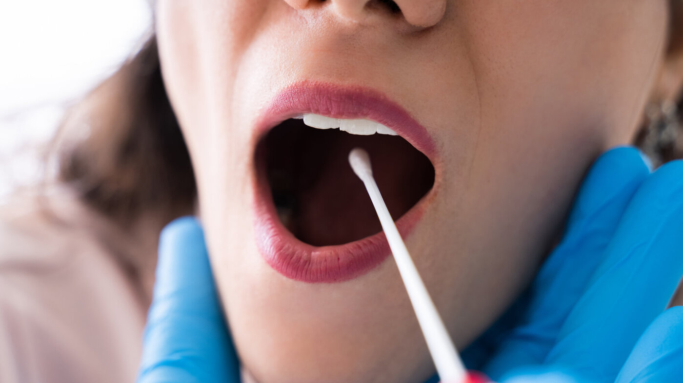 En kvinne blir testet i munnen for Covid-19 