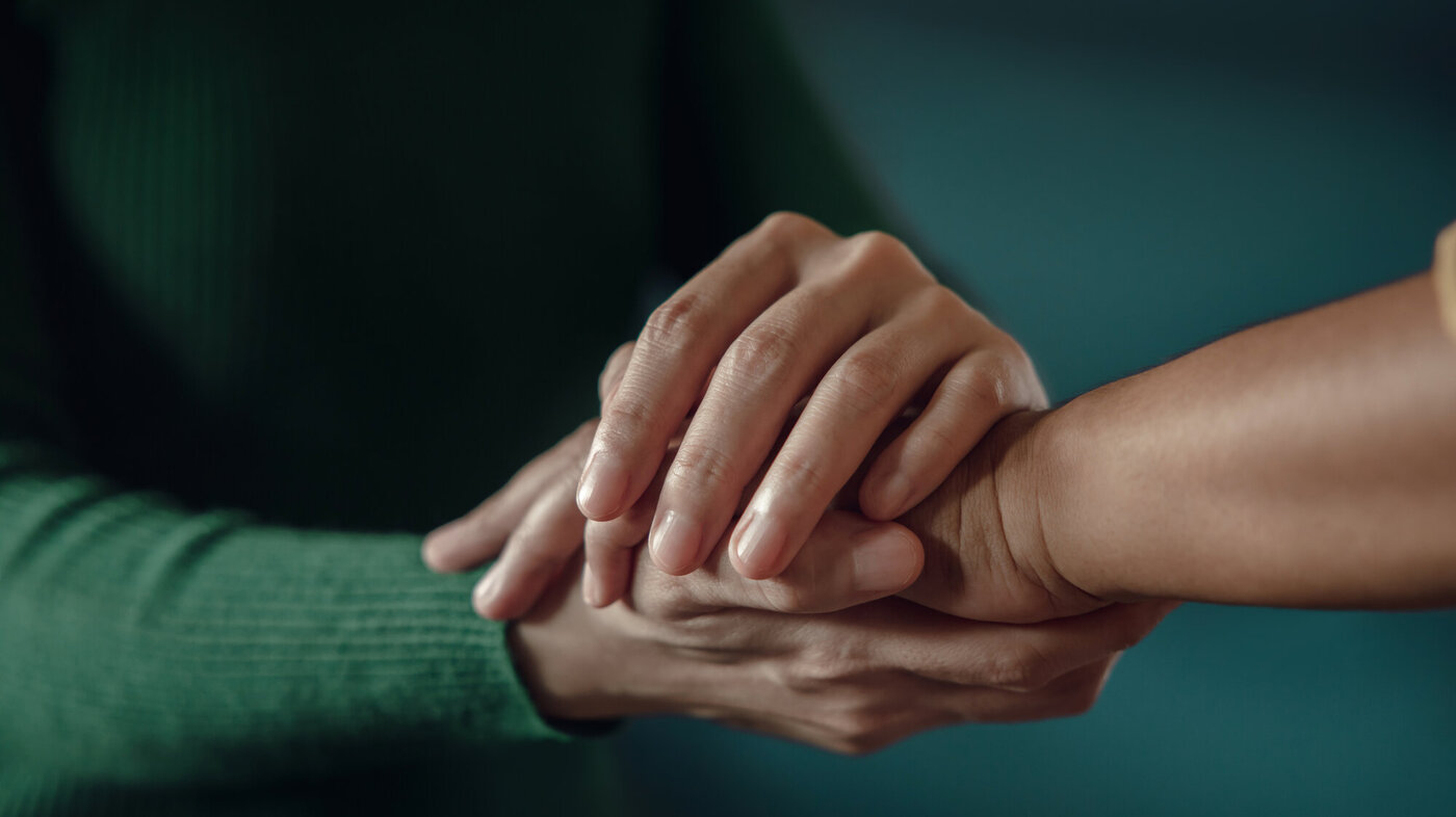 Bildet viser hendene til en kvinne som kjærlig holder rundt en annens hånd.