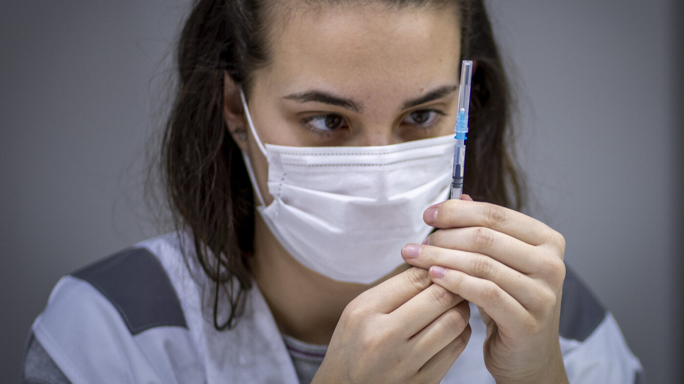Bildet viser en sykepleier som sjekker en ferdig fylt vaksine fra Pfizer/Biontech.