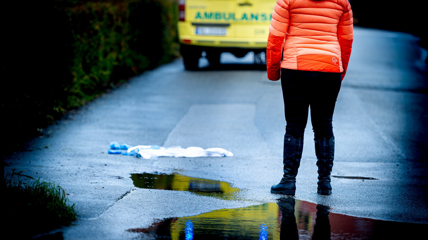 Kvinne står og ser mot ambulanse