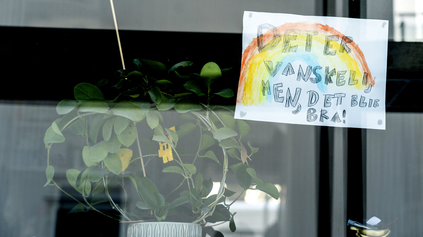Bildet viser en vinduskarm hvor det henger et ark med en tegning av en regnbue og teksten "det er vanskelig, men det blir bra".