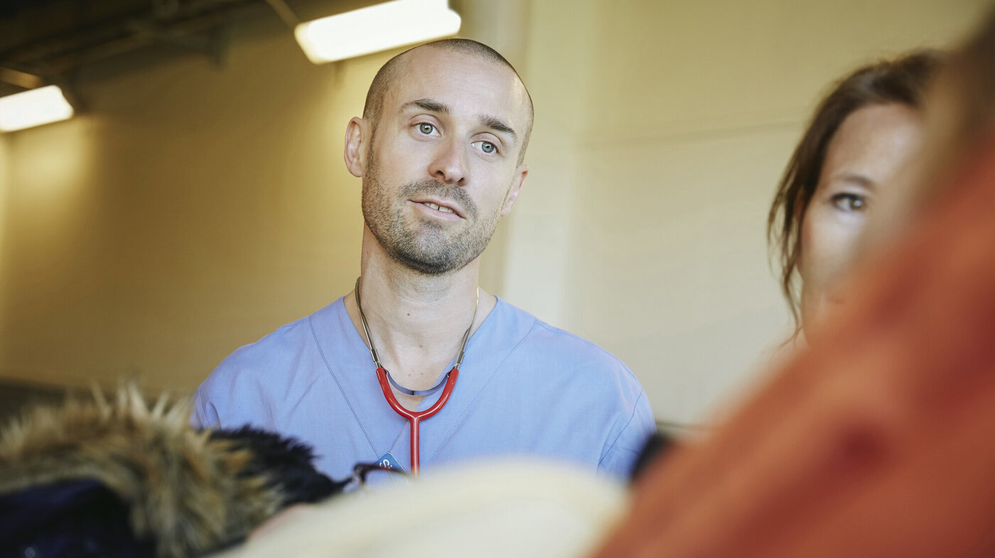 Bildet viser en sykepleier som ser med et godt blikk på en pasient vi bare skimter litt av kroppen til.