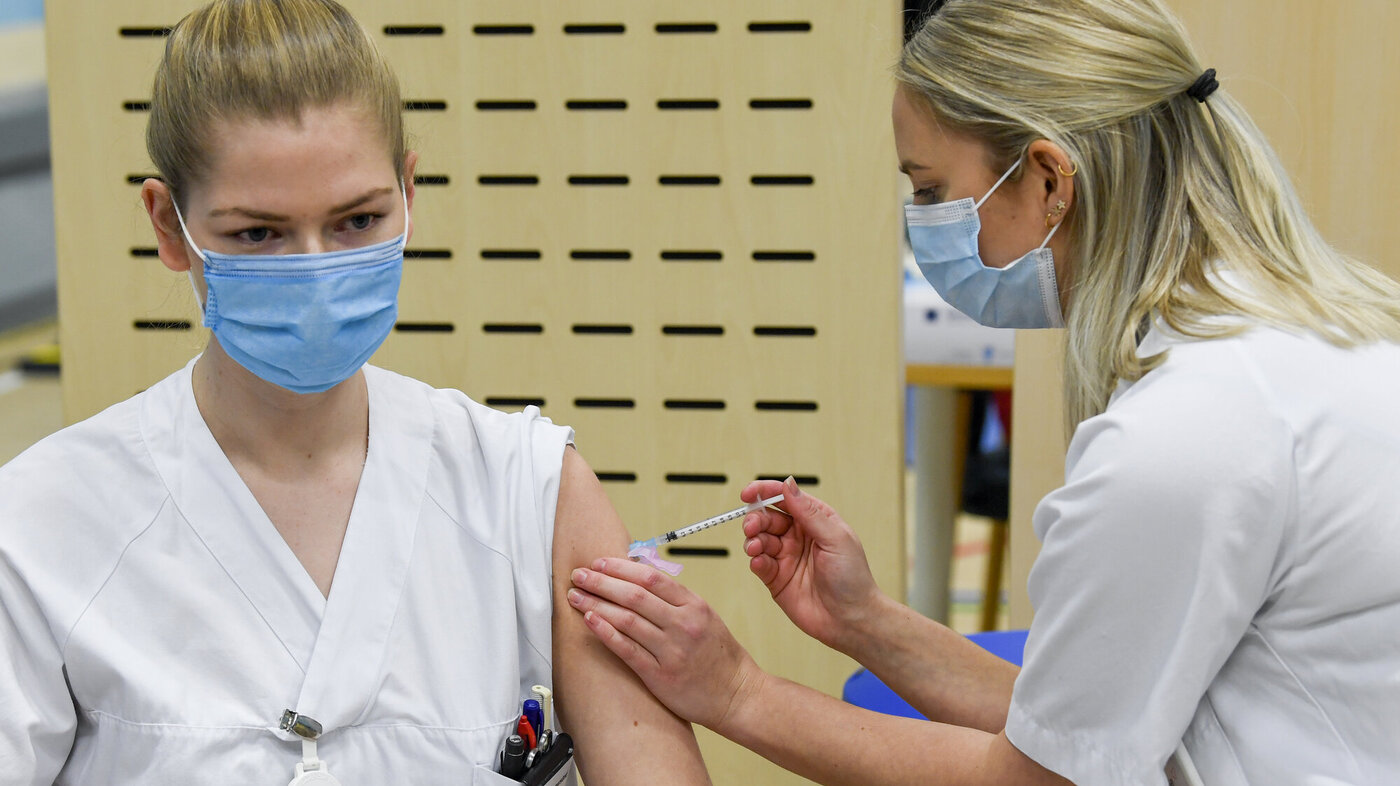 Bildet viser en sykepleier som blir vaksinert av en annen sykepleier.
