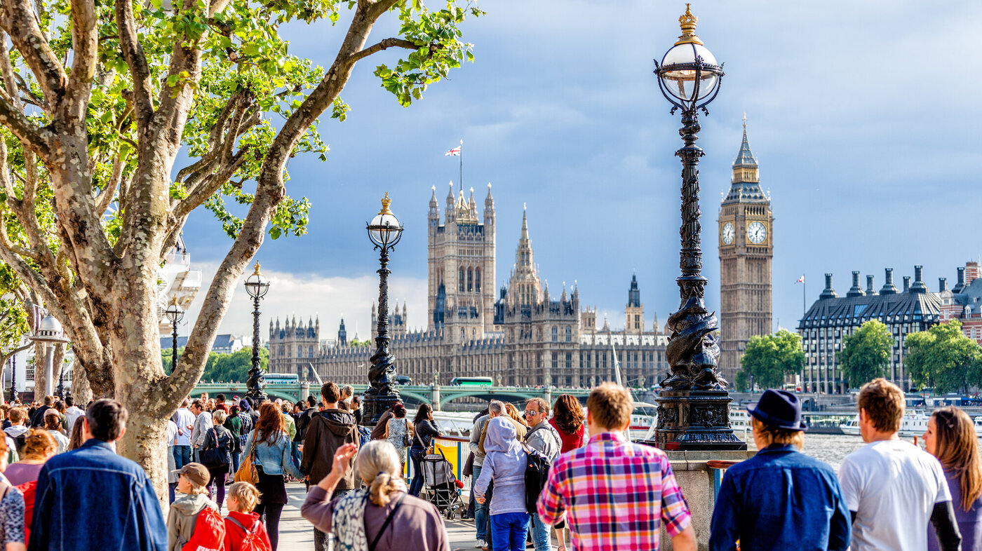 Bildet viser mennesker som går langs Themsen i London, med parlamentet i bakgrunnen