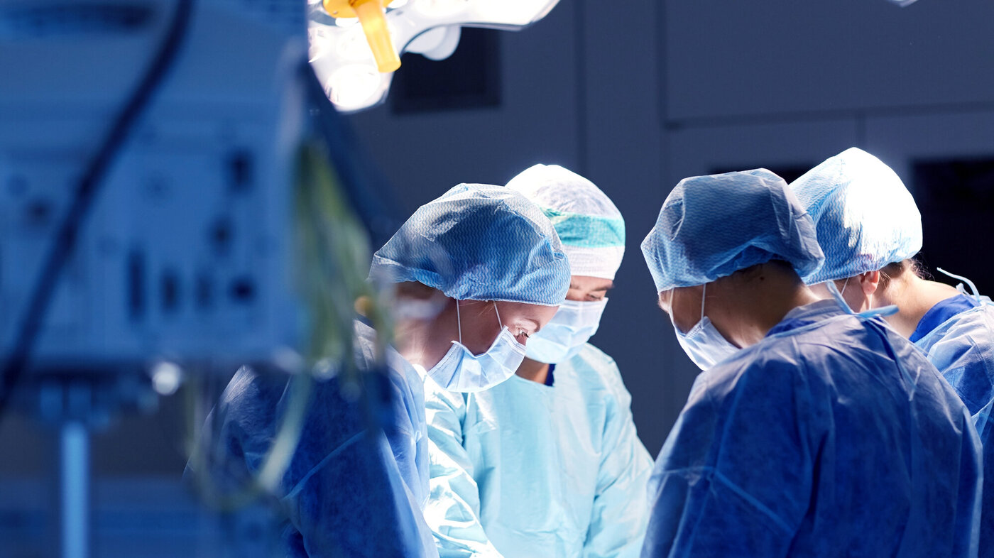 Bildet viser fire helsepersonell i ferd med å operere på en pasient