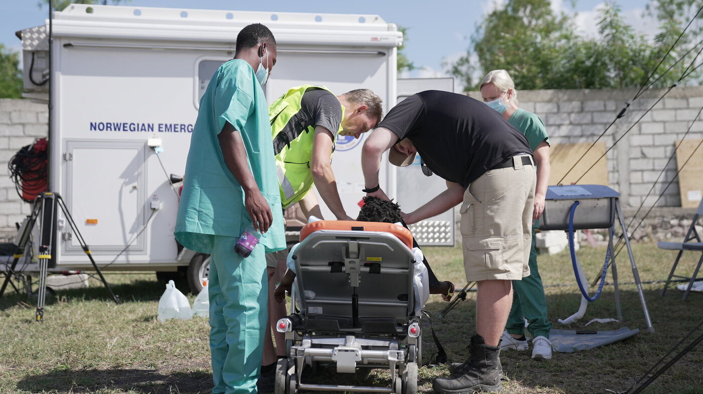 Bildet viser personell på feltsykehuset som gjør en pasient klar for transport til sykehus.
