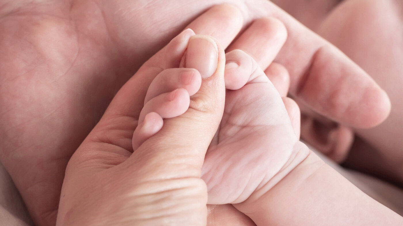 Bildet viser en nyfødt som holder rundt en finger til en voksen