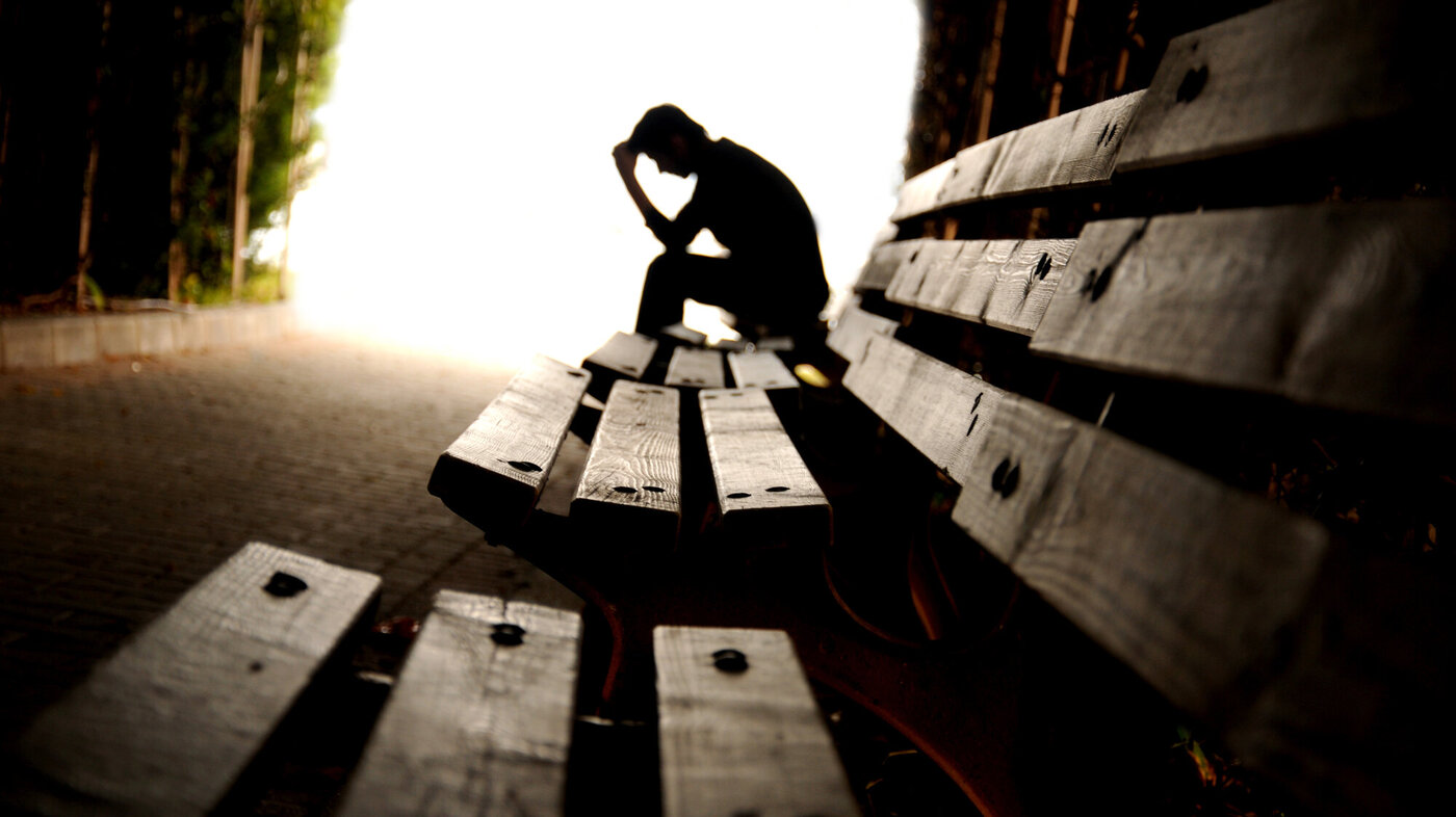 En deprimert mann på en benk. 