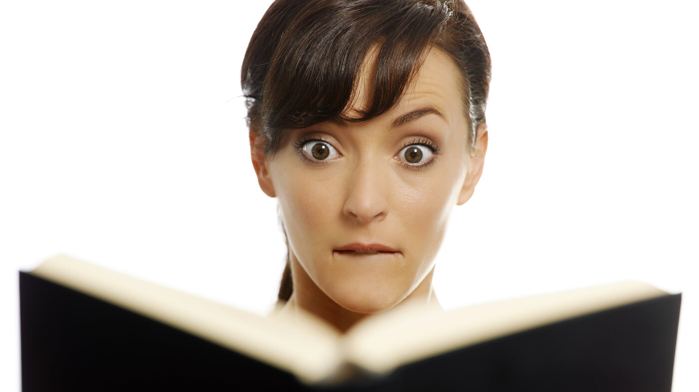 Bildet viser en kvinne som hever øyenbrynene over noe hun leser i en bok