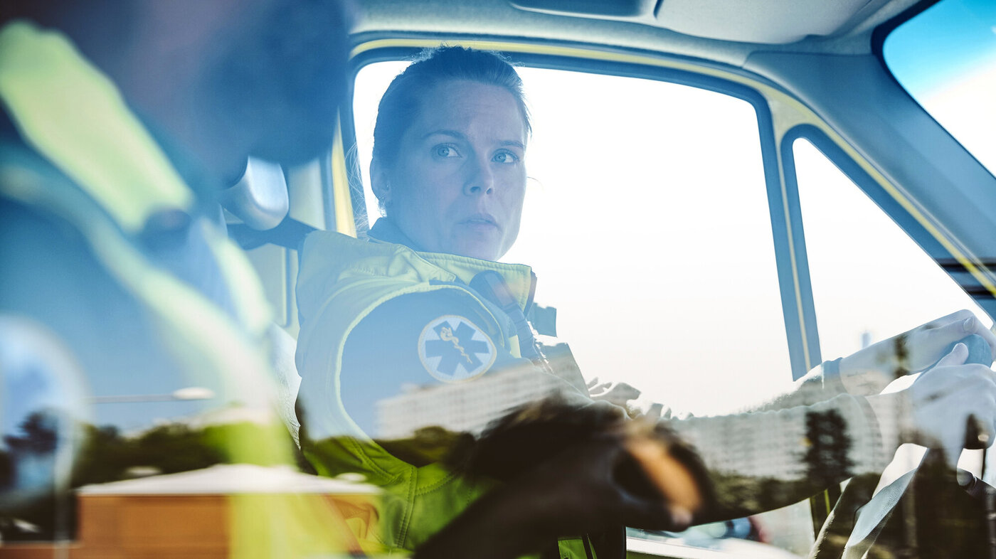 Bildet viser to ambulansearbeidere som sitter i en bil