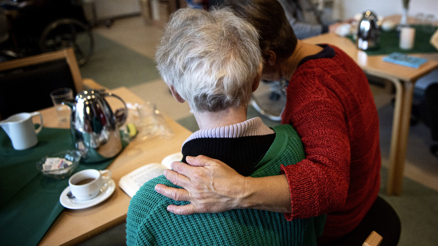 Bildet viser en pleier som holder rundt en pasient på demenspleiehjemmet Dagmarsminde i Danmark