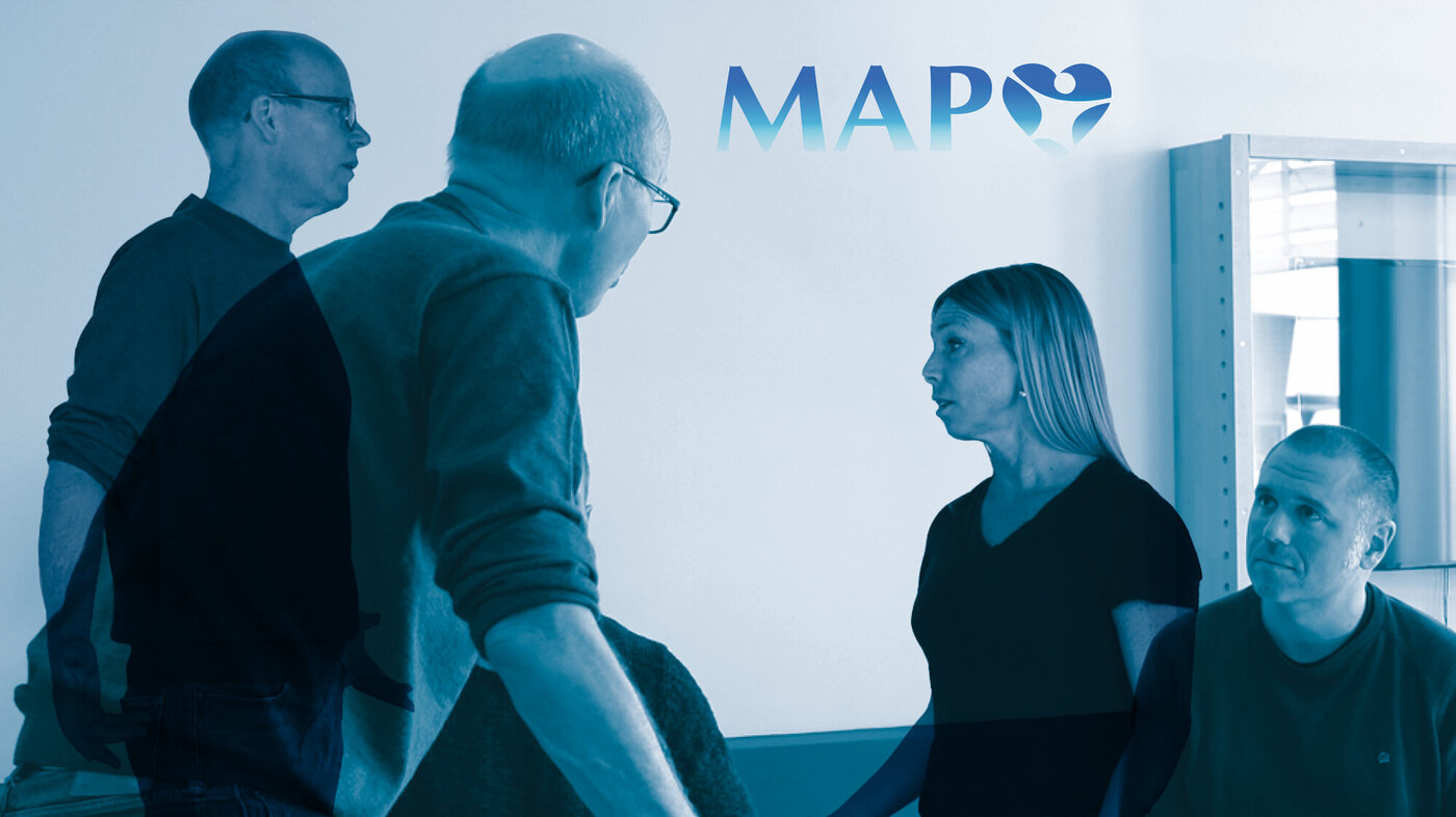 Deescalation training The image shows four people training on deescalation. In the background the MAP logo can be seen