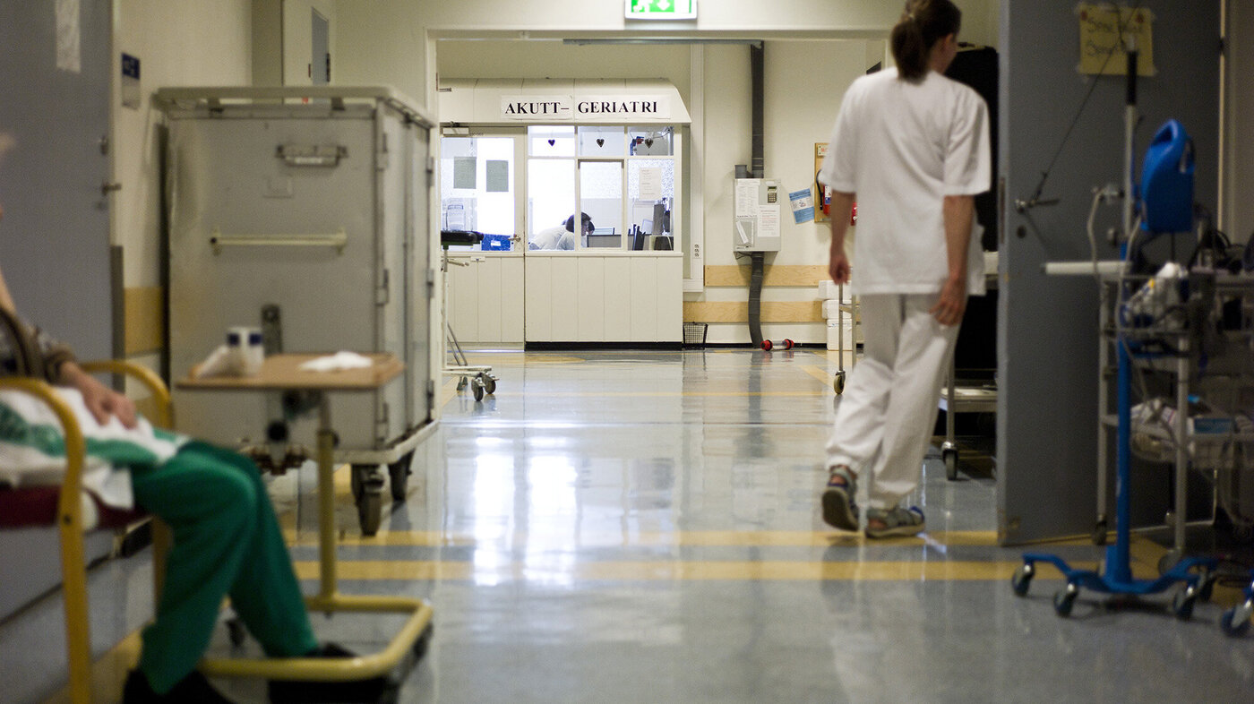 Bildet viser en sykepleier og en pasient i en sykehuskorridor