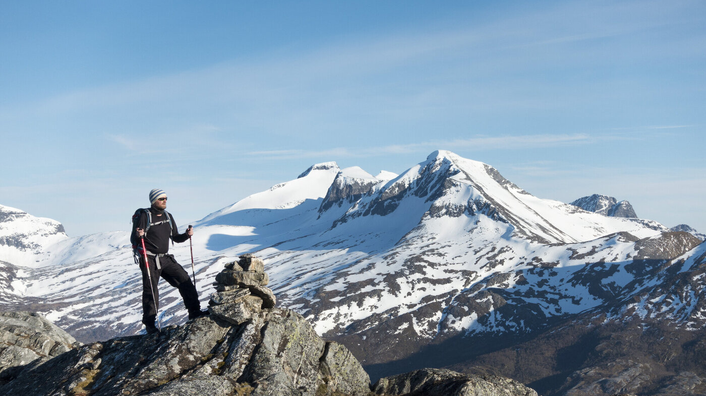 Bildet viser en mannlig turgåer som står på en fjelltopp