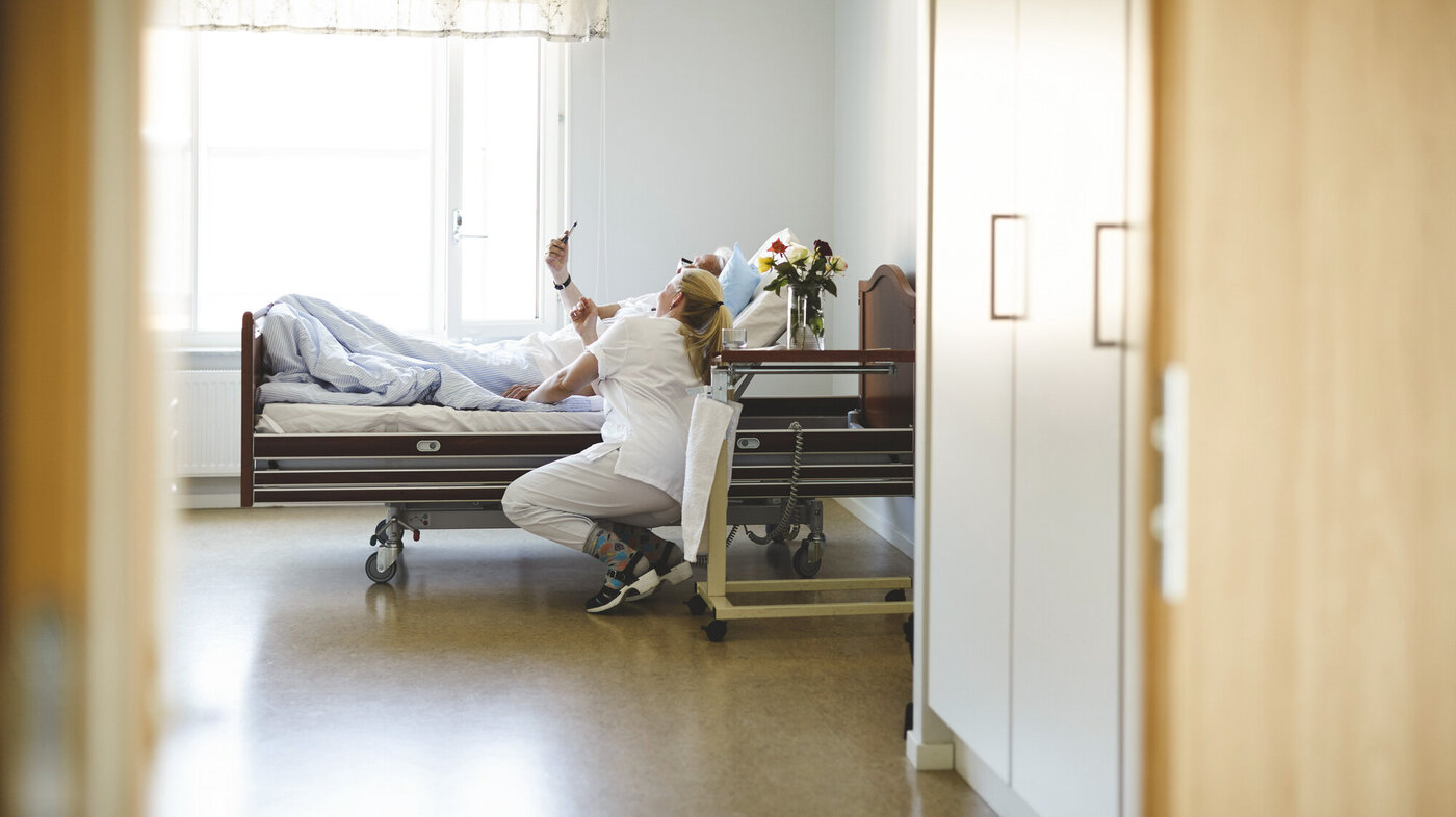 Bildet viser en sykepleier og en pasient som ser på mobilen sammen