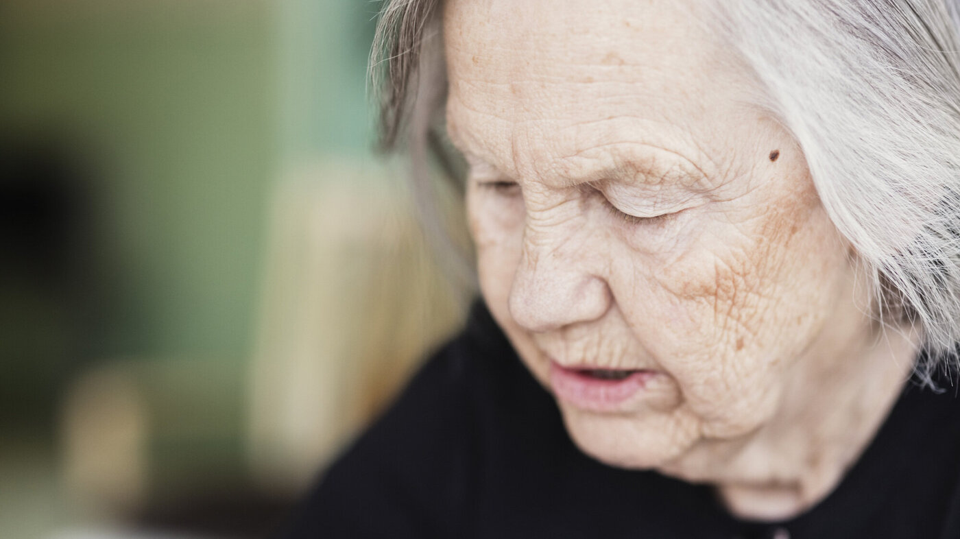 Bildet viser en tankefull eldre kvinne