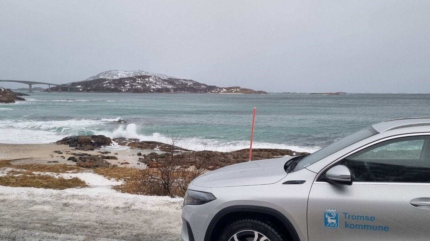 Bildet viser en bil parkert nede ved havet med Sommerøybrua og Sommerøy i bakgrunnen