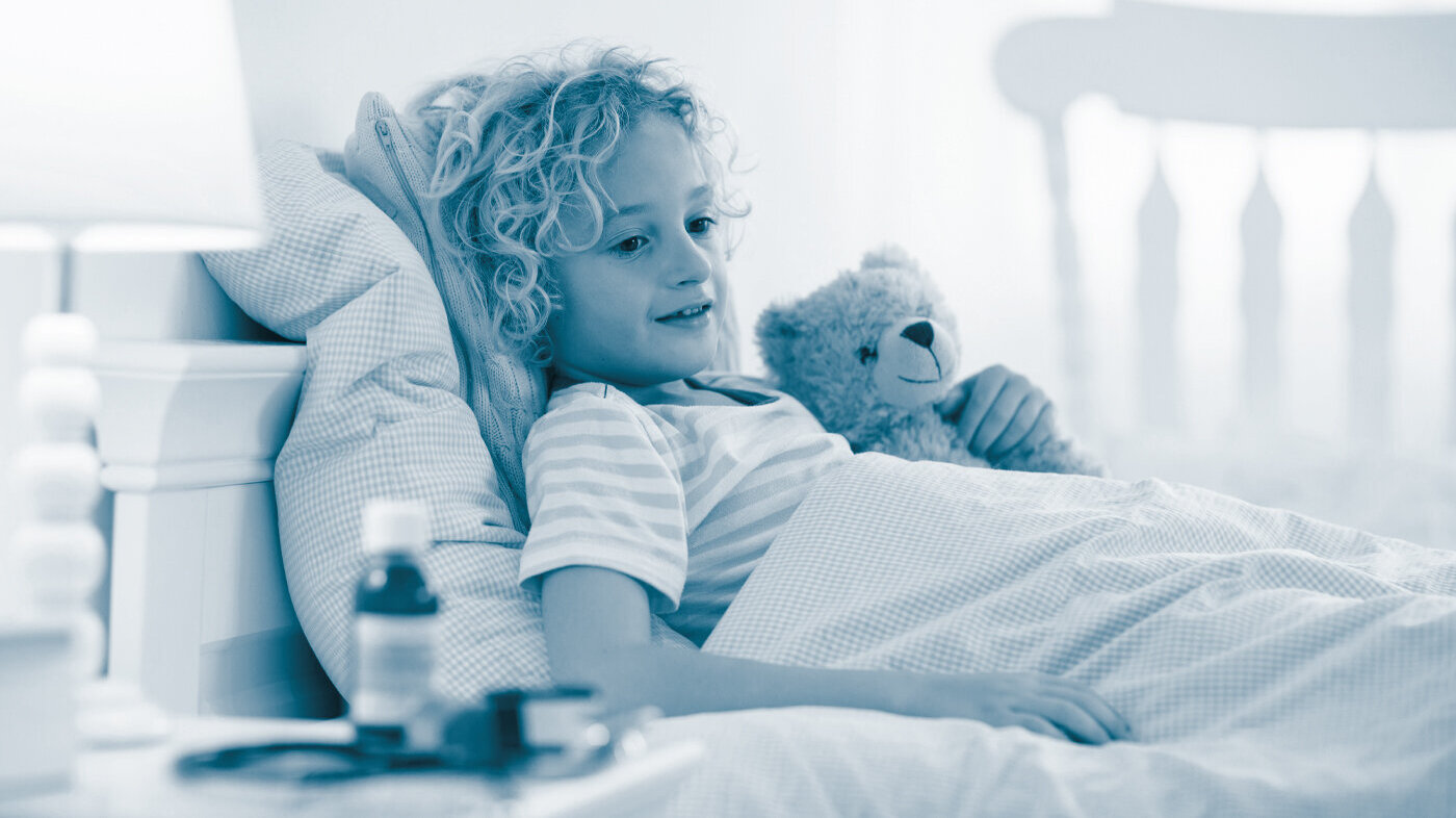 Child in palliative care The photo shows an ill, little boy lying in his bed. In his handen he is holding a teddy bear. There are medicine bottles on the bedside table.