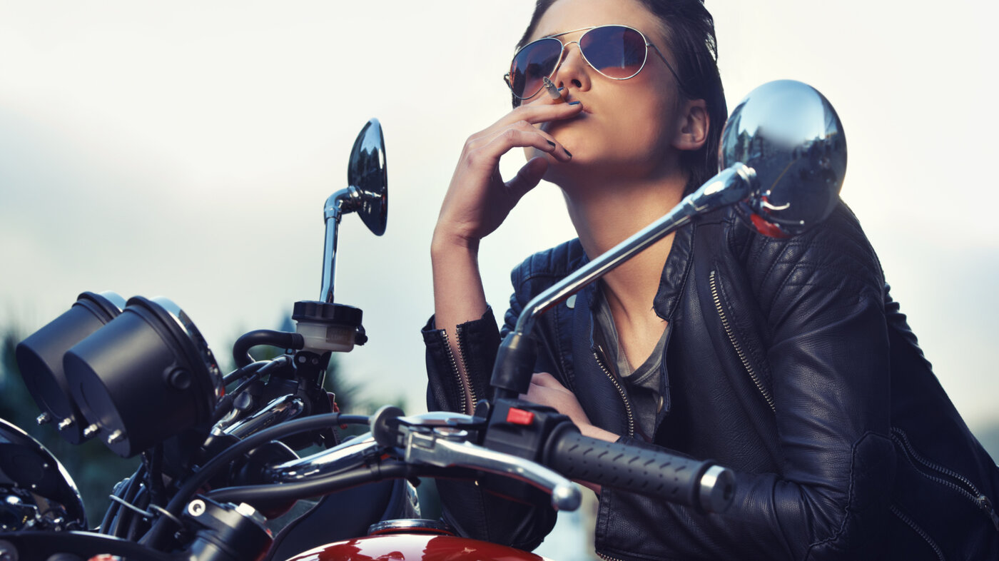 Bildet viser en dame på motorsykkel som røyker