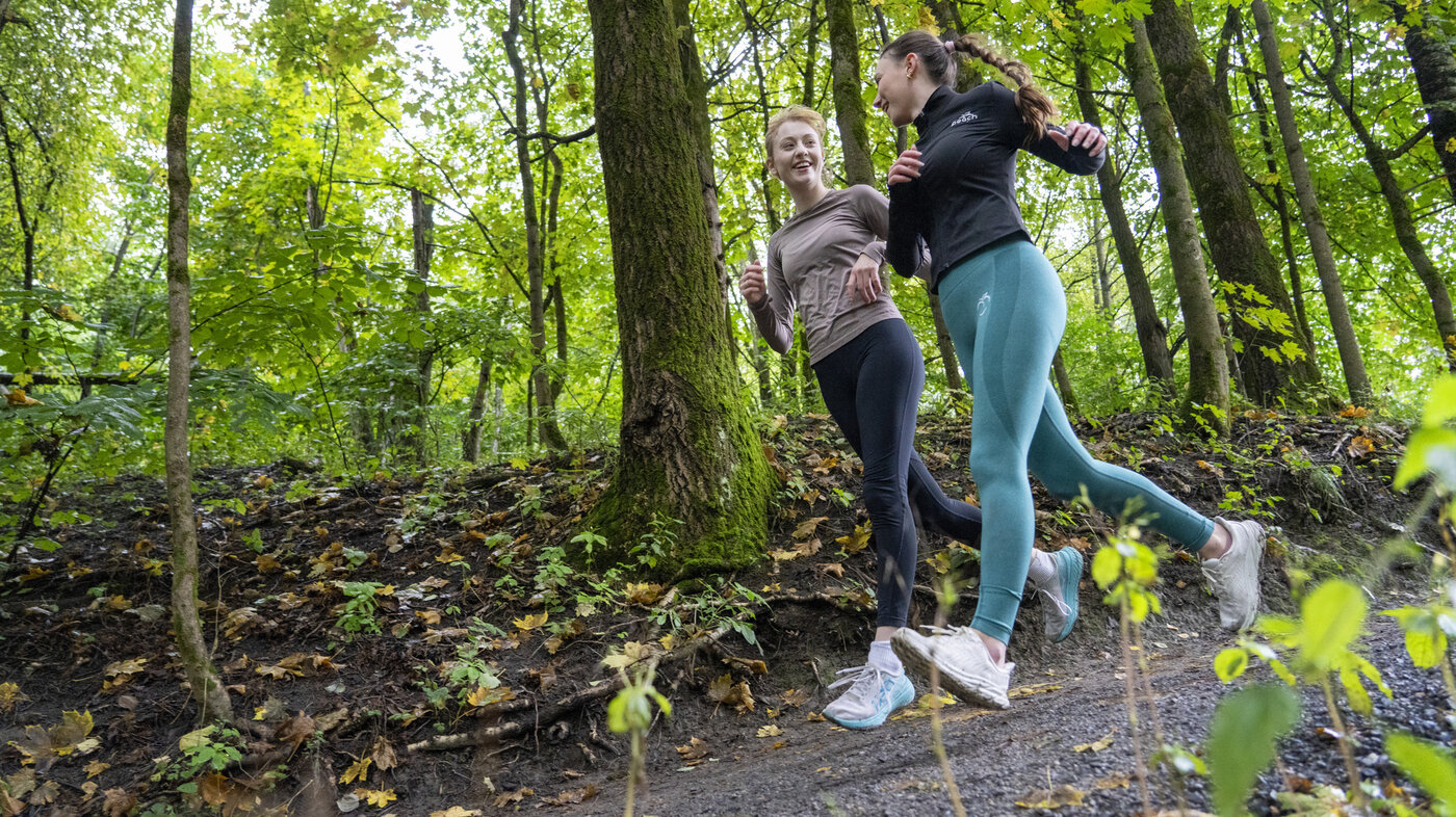 Bildet viser to unge kvinner som jogger i skogen.