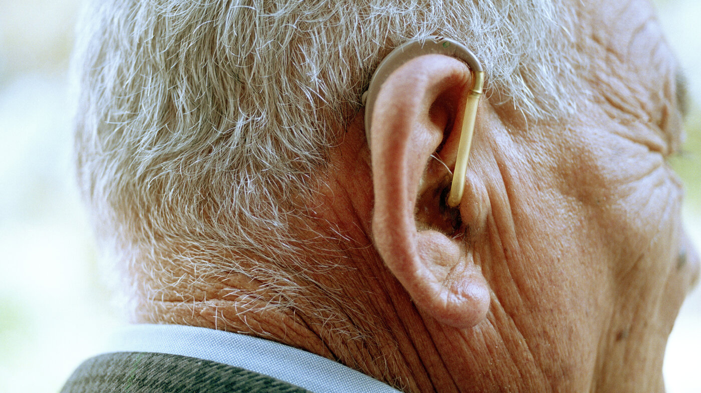 Bildet viser en eldre mann med høreapparat.