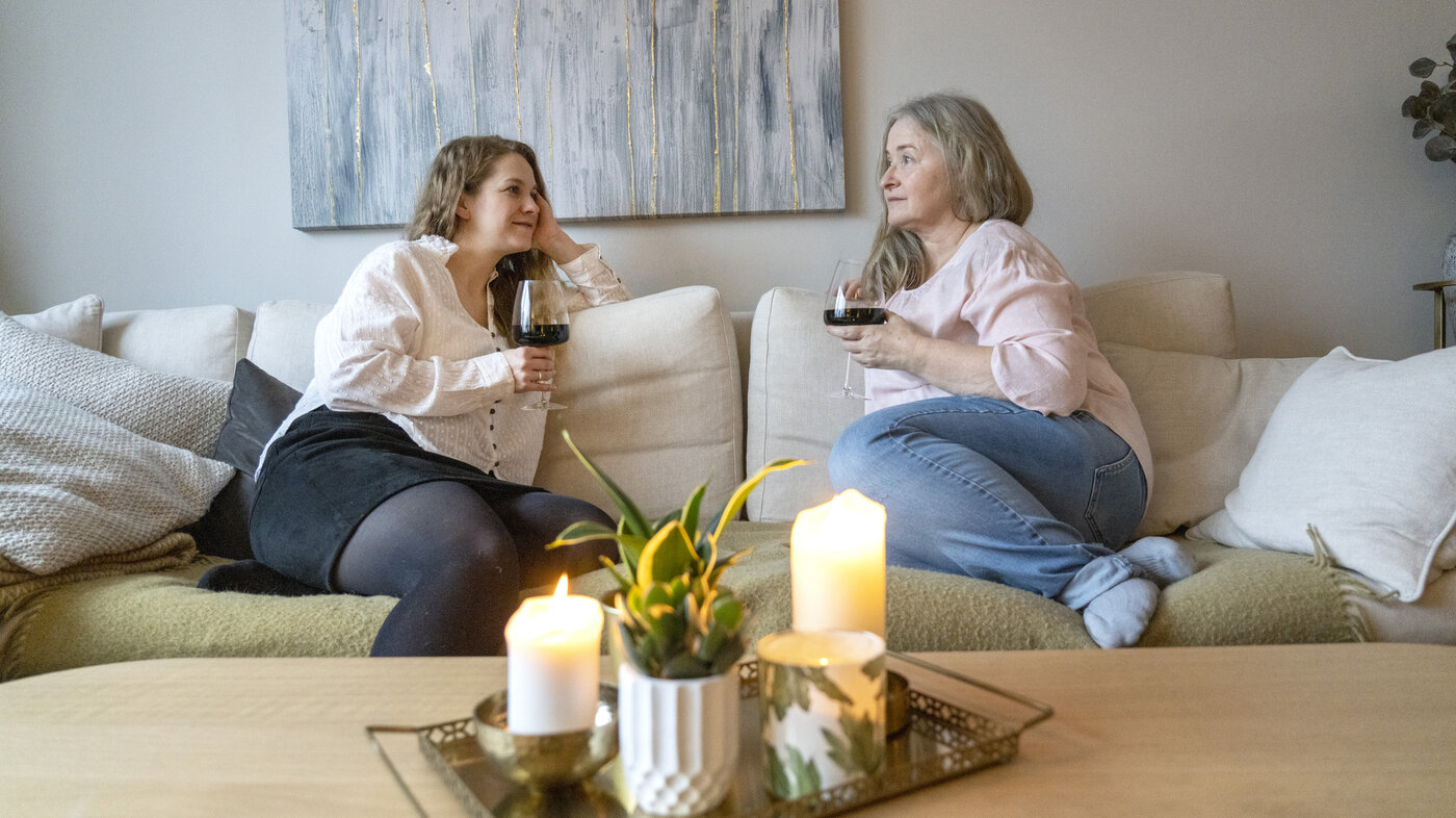 Bildet viser to kvinner som drikker vin i sofaen.