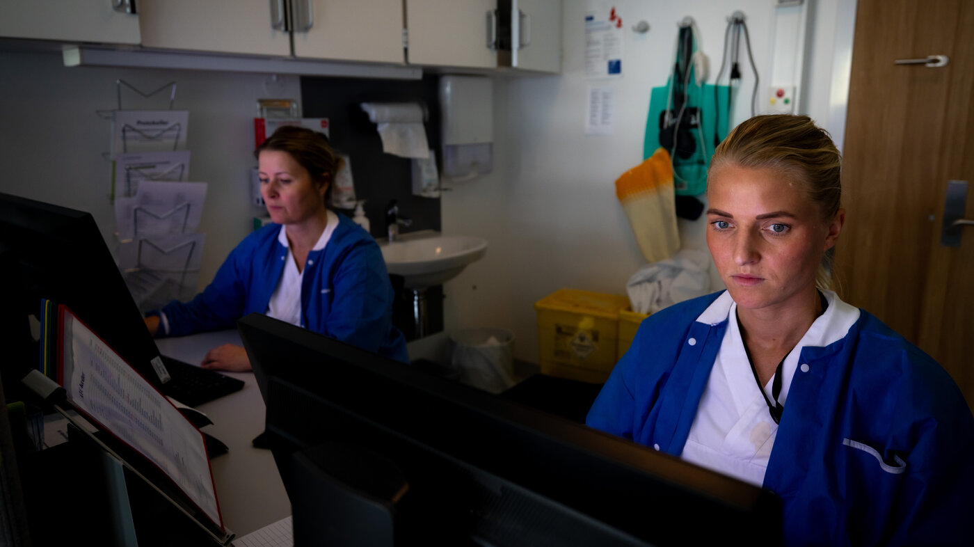 The photo shows two nurses in front of a computer each.