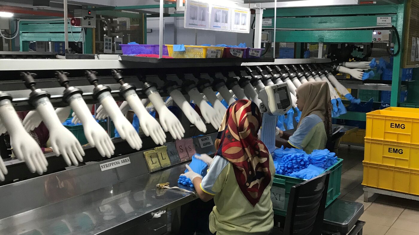 Bildet viser arbeidere på en hanskefabrikk i Malaysia.