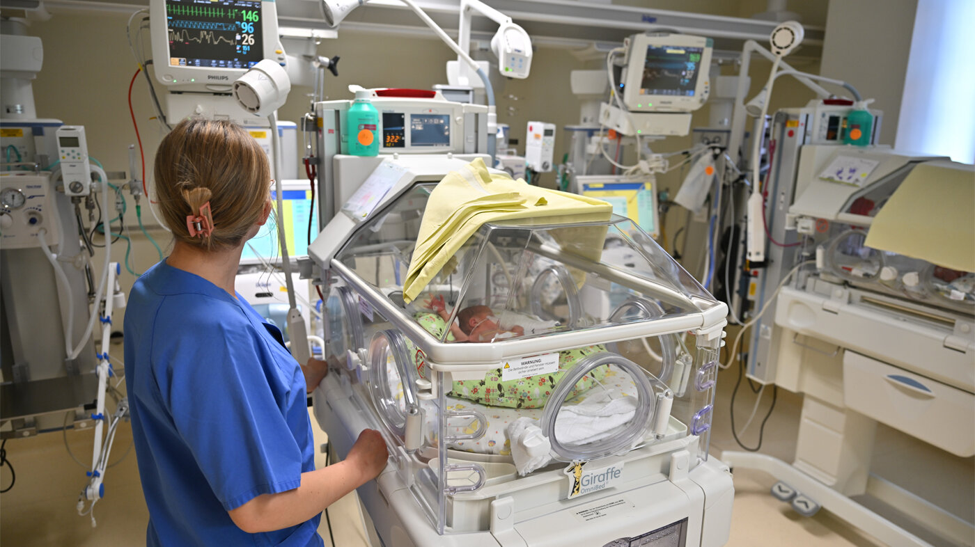 Bildet viser en sykepleier og et ekstremt prematurt barn i et høyteknologisk sykehusmiljø