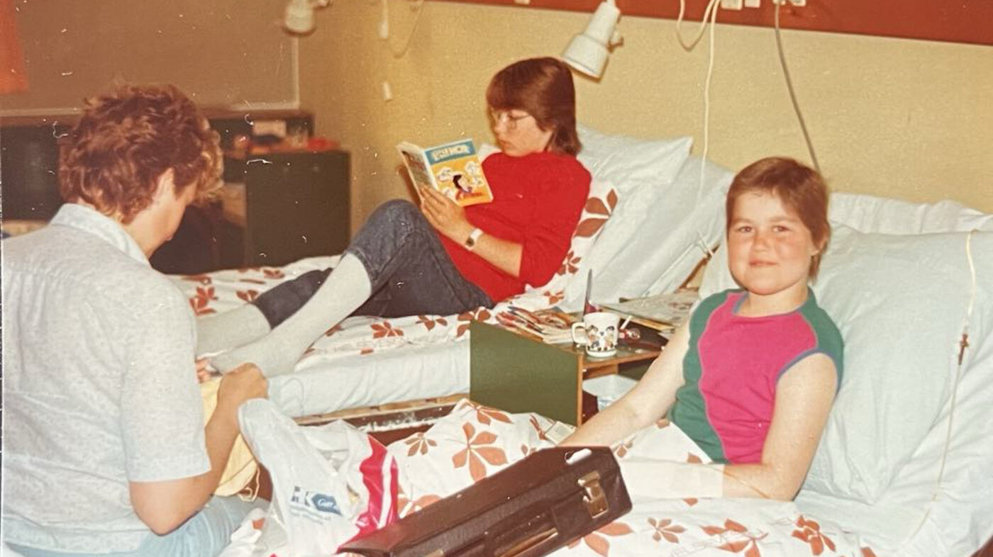 Privat Barn på sykehus som får besøk av familien sin. søsteren og mammaen sitter i sengen sammen med henne