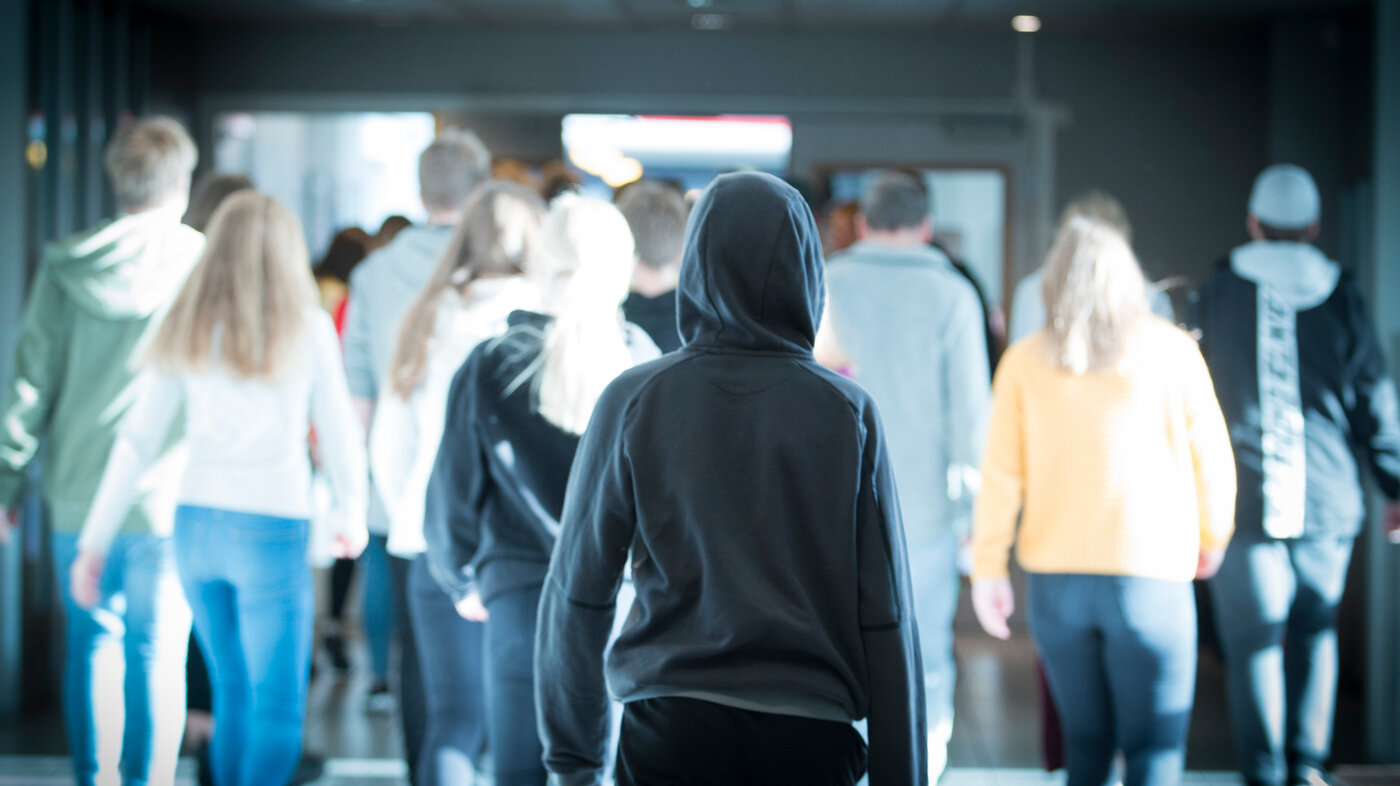 Viser ungdommer som går inn i et bygg bakfra Viser ungdommer som går inn i et bygg bakfra