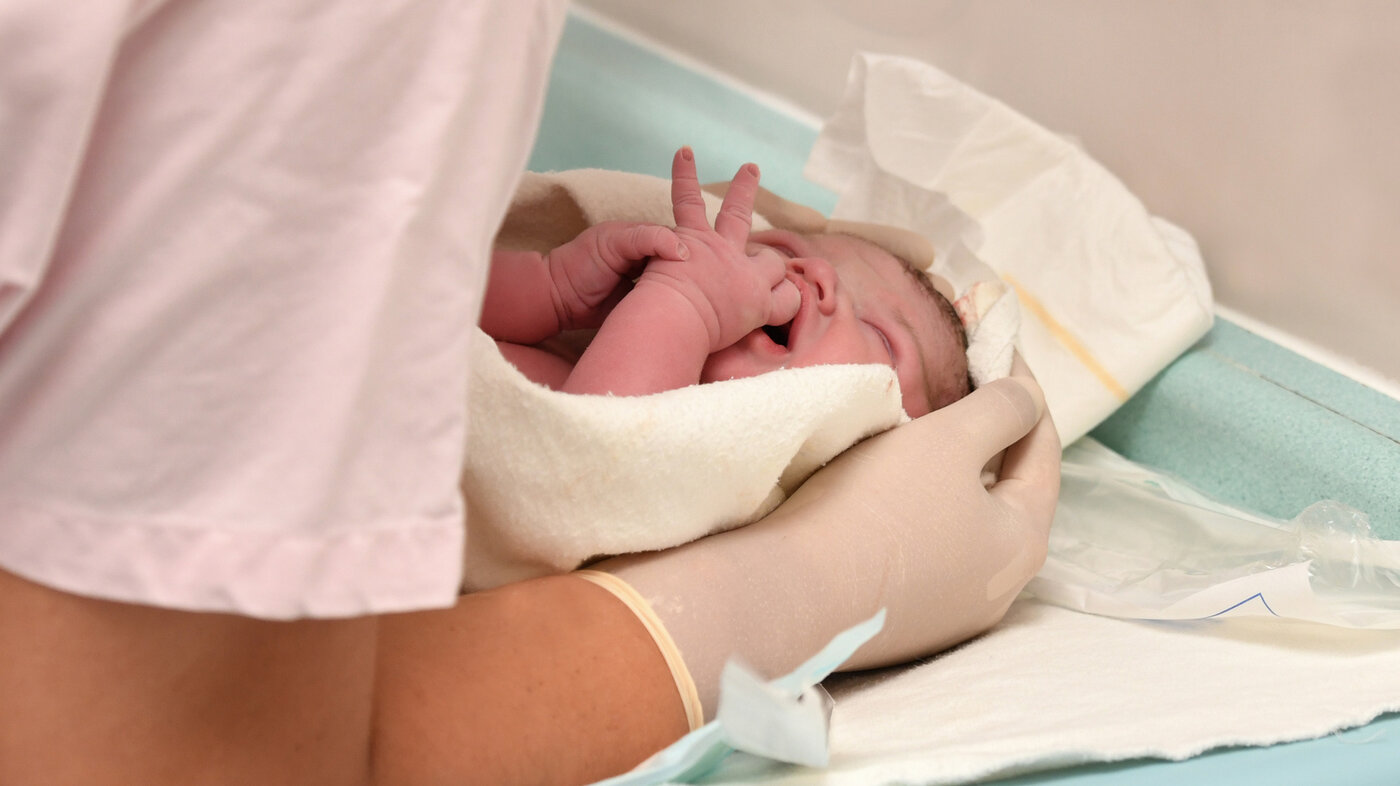 Helsepersonell, barsel, baby Bildet viser helsepersonell som holder i en nyfødt baby.