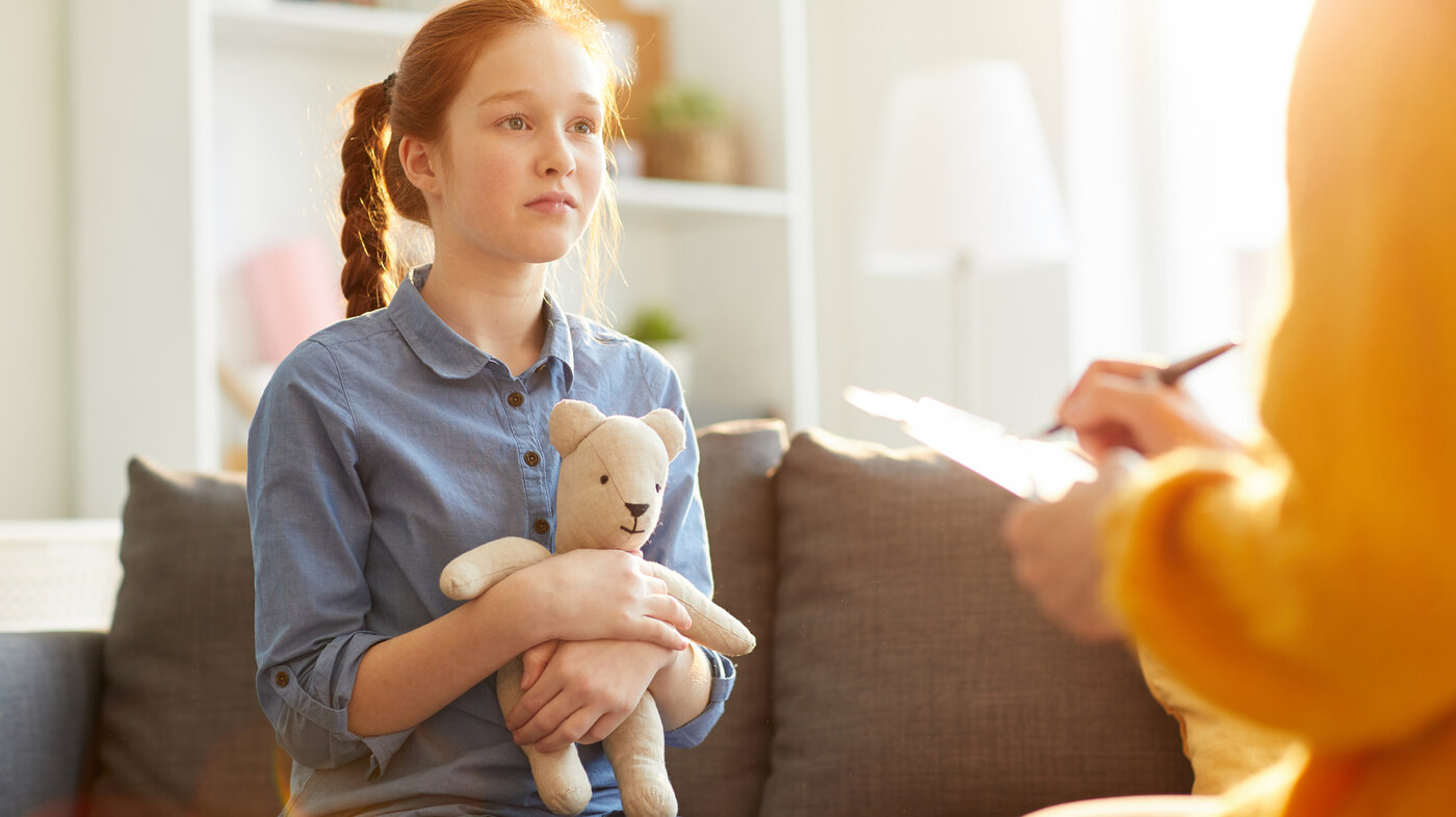 Bildet viser en trist jente som snakker med en helsesykepleier