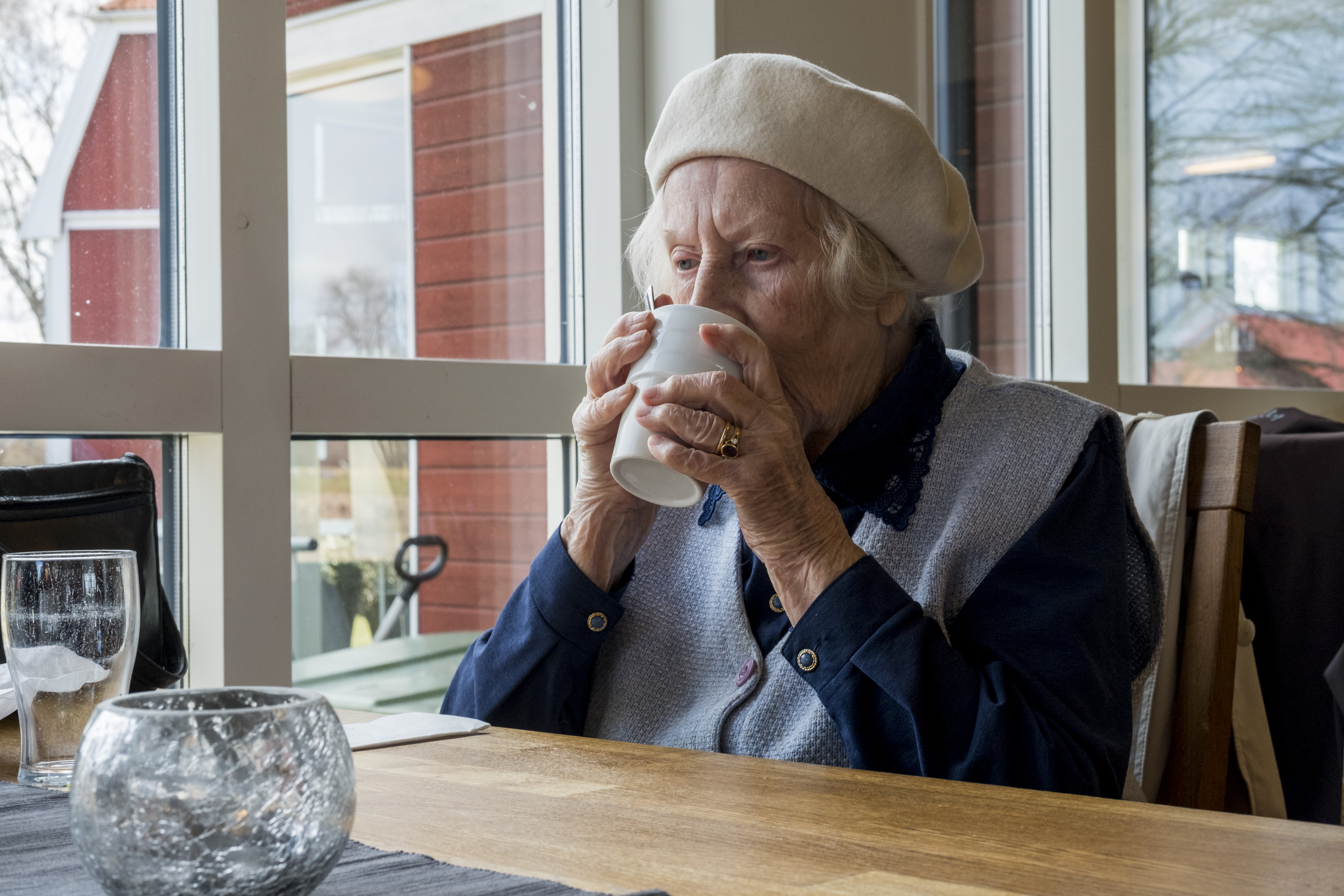 Bildet viser eldre kvinne som drikker av kopp