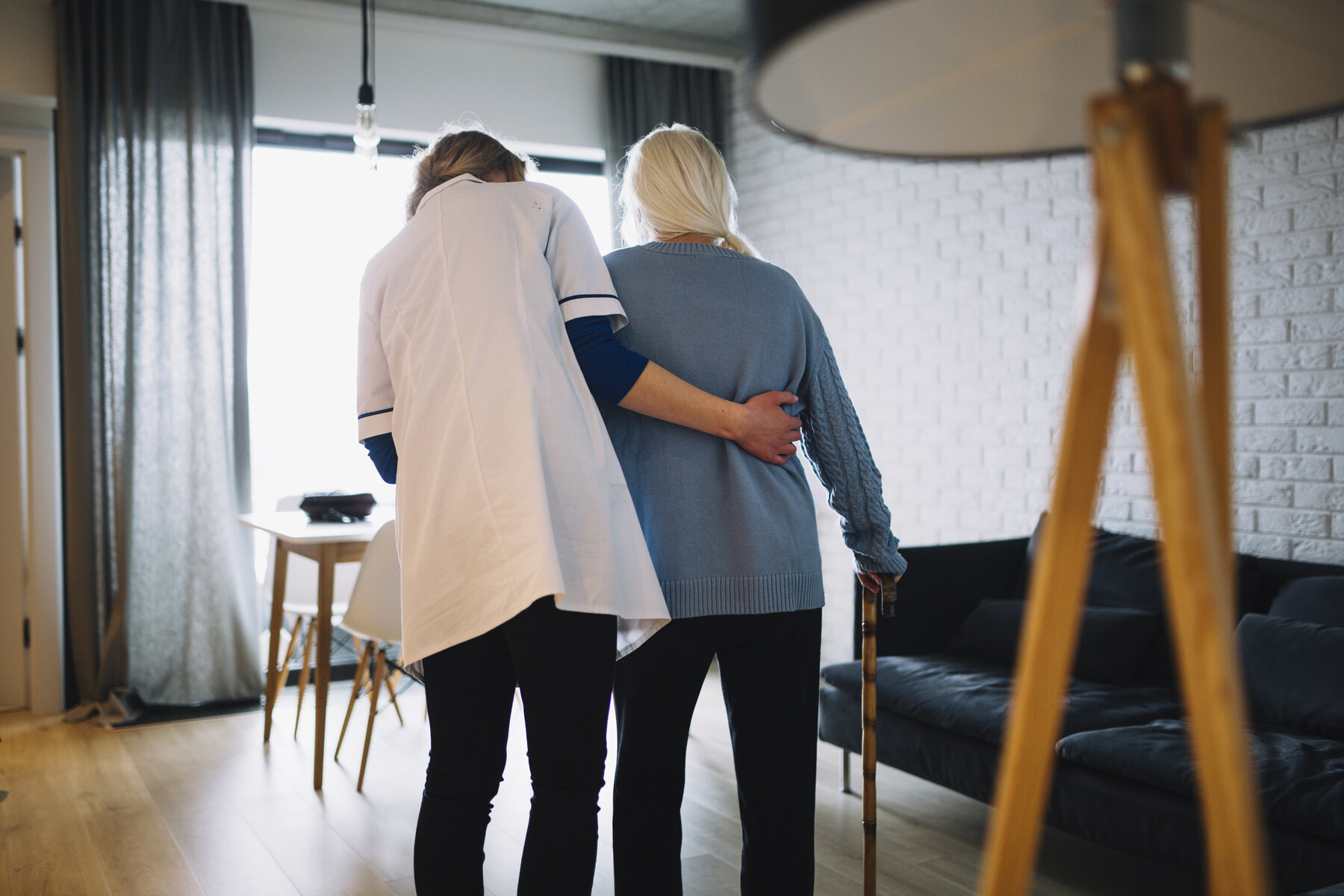 Pleier og eldre Bildet viser en pleier som støtter en eldre pasient